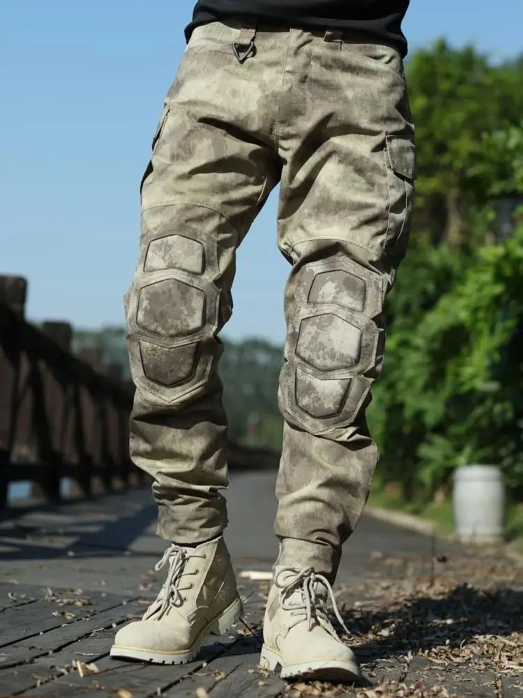 Un hombre que usa pantalones de camuflaje de pie en un puente de madera