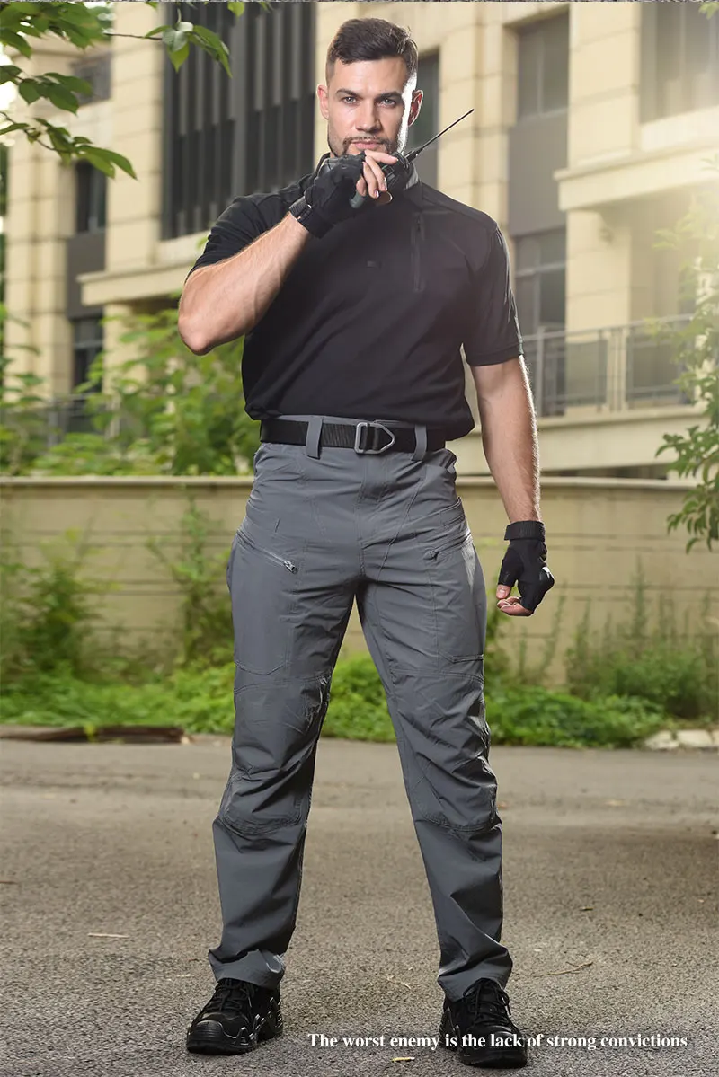 Un hombre que usa una camisa negra y pantalones grises fumando un cigarrillo