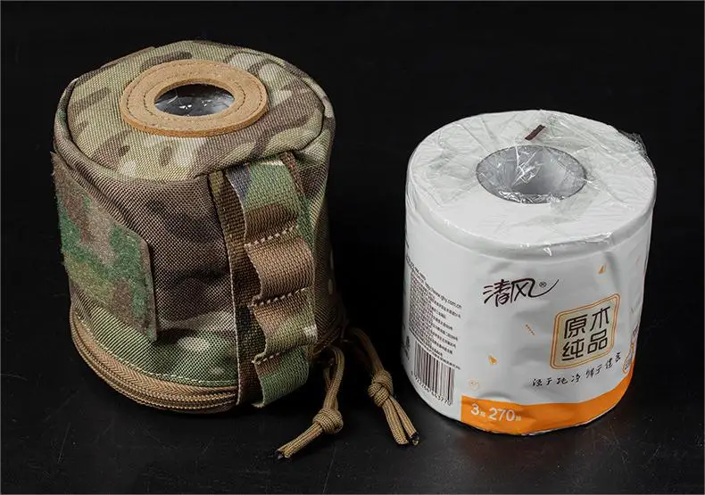 Una bolsa de camuflaje se sienta junto a un rollo de papel higiénico
