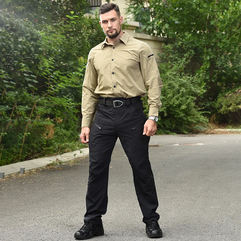 Un hombre que usa una camisa marrón y pantalones negros se encuentra en una carretera