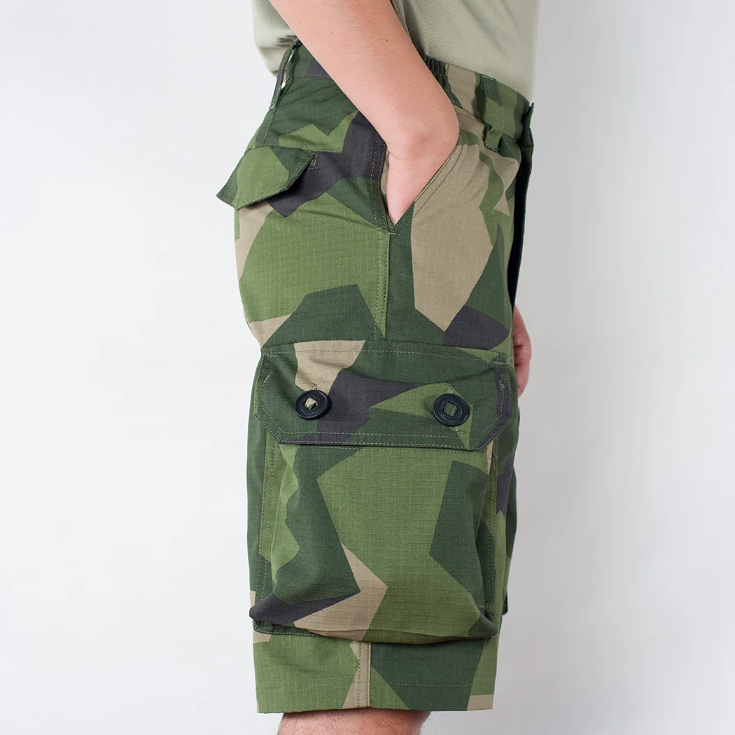 Un hombre con pantalones cortos de camuflaje con las manos en los bolsillos