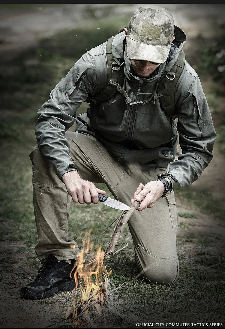 Un hombre con una chaqueta de camuflaje está arrodillado y afilando un cuchillo