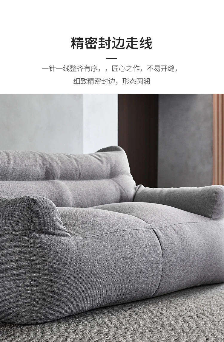 Un sofá gris con una pared en blanco y negro detrás