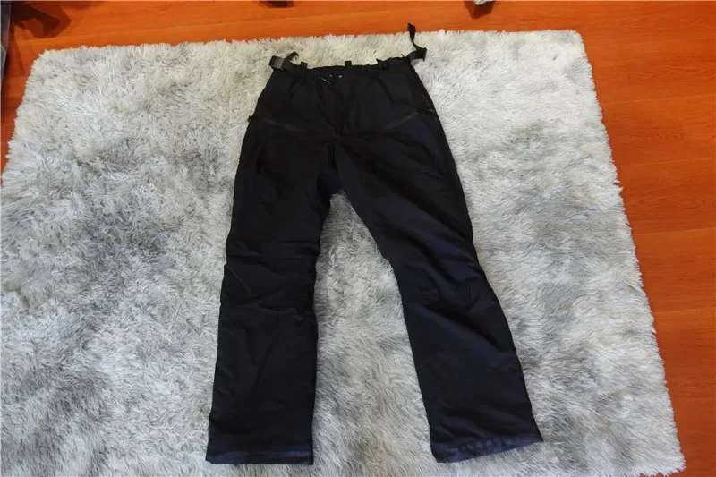 Un par de pantalones negros que se encuentran en una alfombra blanca