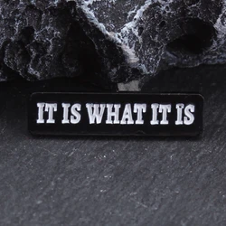 Broche de metal táctico con inscripción Es lo que es