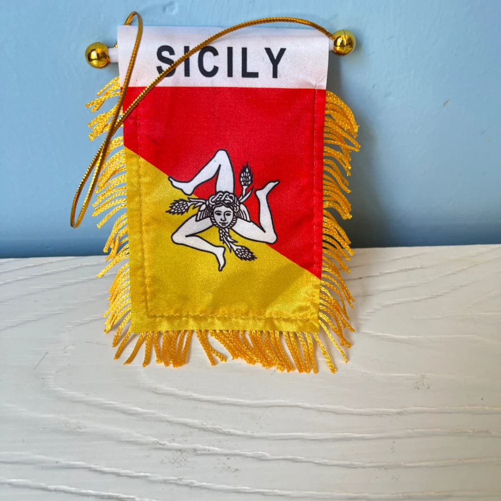 Bandera siciliana colocada como decoración en una ventanilla lateral de coche