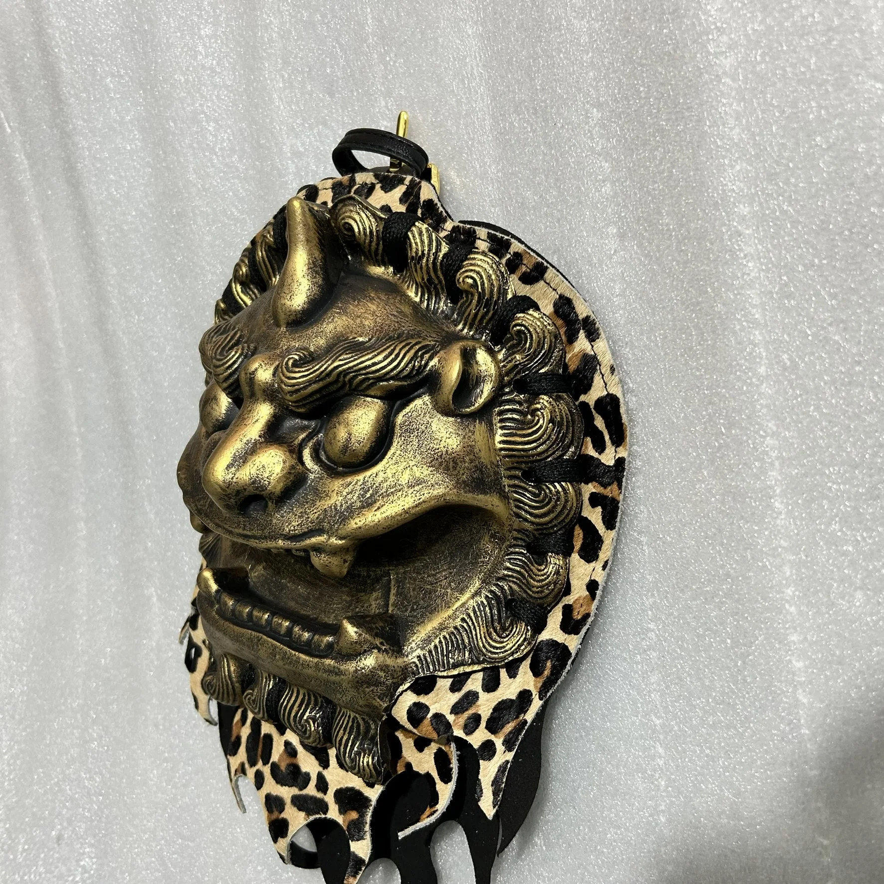 Detalle frontal del protector de vientre con escamas doradas y ojos del león