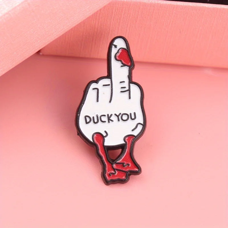 Detalle del pin esmaltado con mano de gesto humorístico y pico rojo