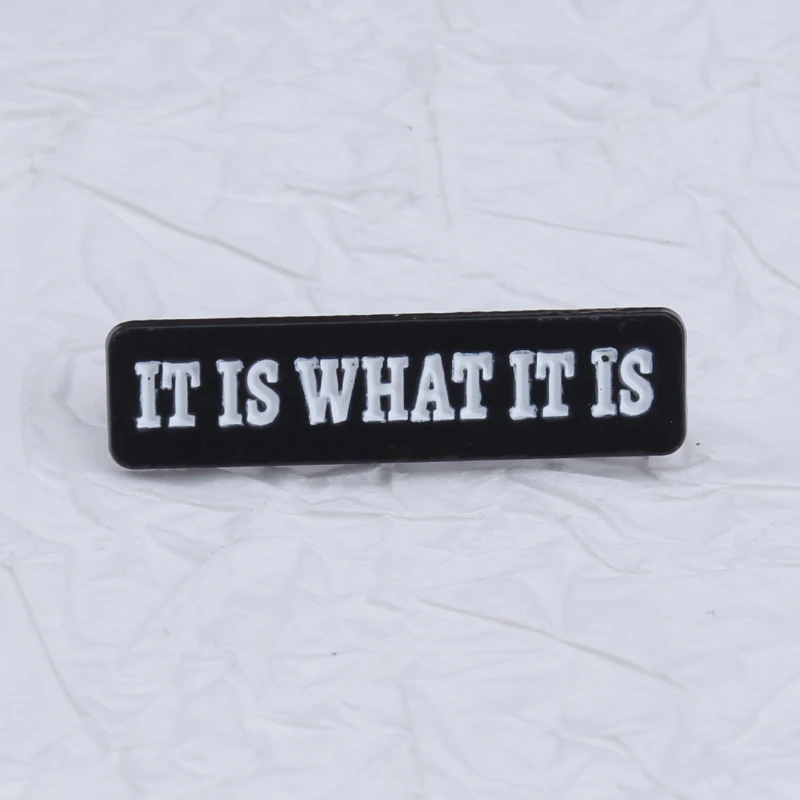 Broche de metal táctico con inscripción Es lo que es