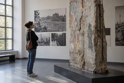 Visitante contemplando un fragmento de muro en una exposición histórica ficticia